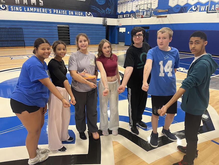 (from left to right) - Payton Harvey, Aubria Holmes, Camilla Fluery, Meredith LeSage, Christiano Vijelie Lixanderu, Michael Murray, and Keshawn Tucker posing with their signed arm by guest speaker Wyland.