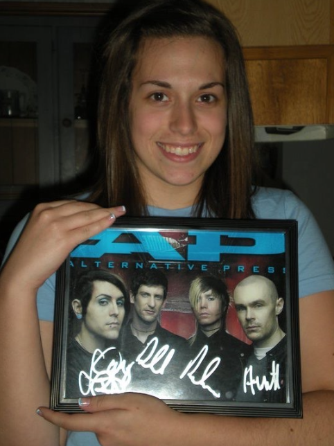 Mrs. Lyon when she was younger holding up a signed picture of a band she used to like.
