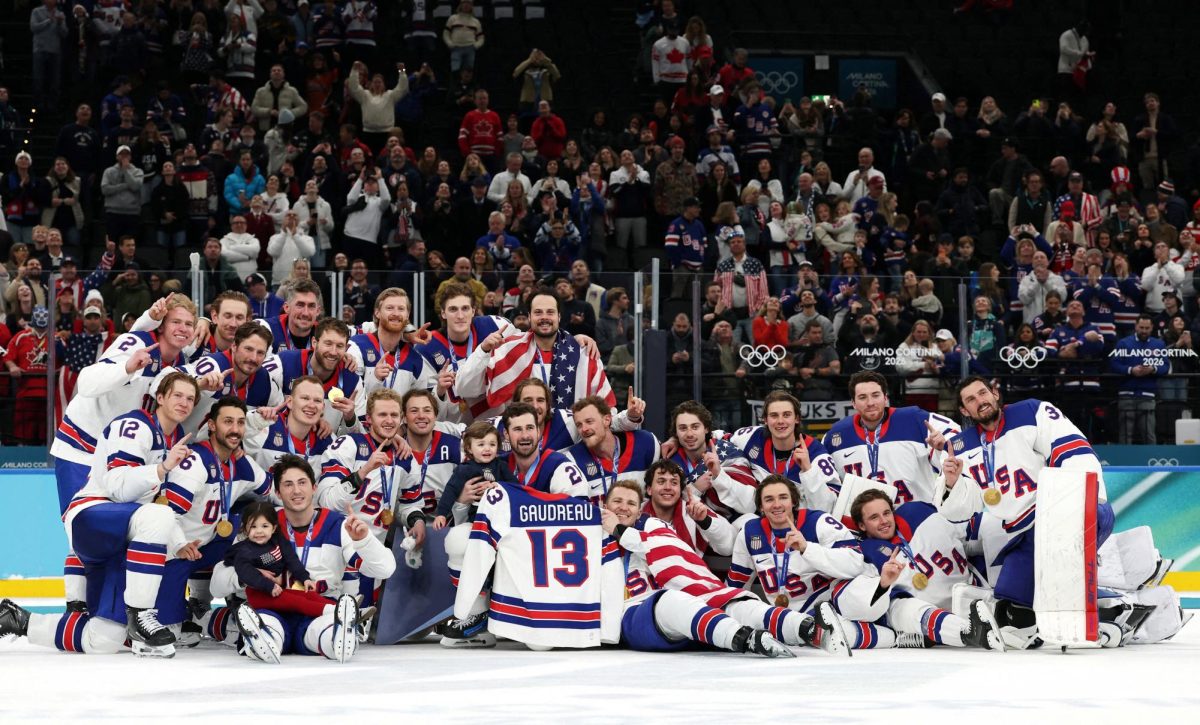 Milano Cortina 2026 Olympics - Ice Hockey - Men's Victory Ceremony - Milano Santagiulia Ice Hockey Arena, Milan, Italy - February 22, 2026. Gold medalists United States hold up the jersey of the late John Gaudreau and celebrate with his children, Noa Harper Gaudreau and Johnny Edward Gaudreau, as they pose for a photograph and celebrate with their medals during the ceremony REUTERS/Mike Segar
